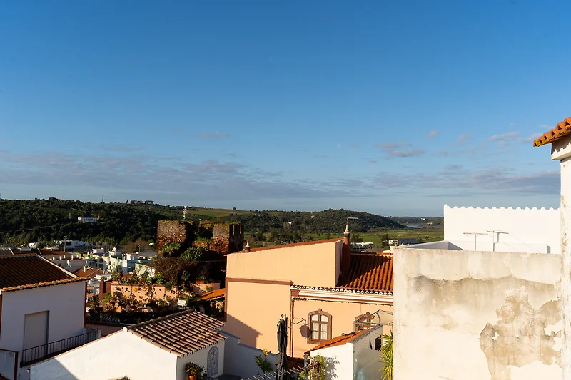 Genießen Sie den Ausblick vom Balkon über Dächer und den weiten Horizont.