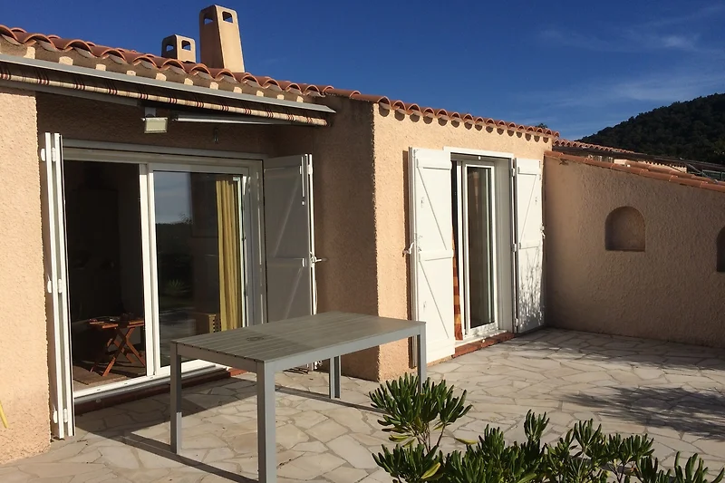 Überdachte Terrasse mit Tisch, Stühlen und direktem Zugang zum Haus.