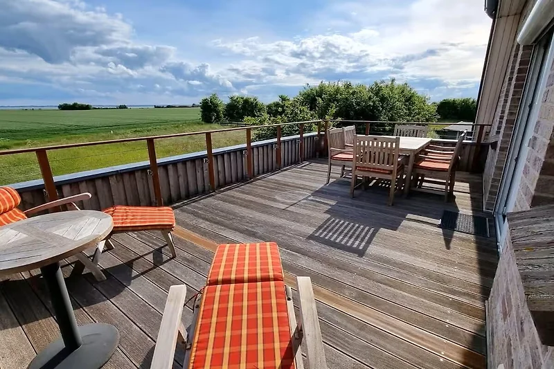 Holzveranda mit Outdoor-Möbeln und schattigem Blick ins Grüne.