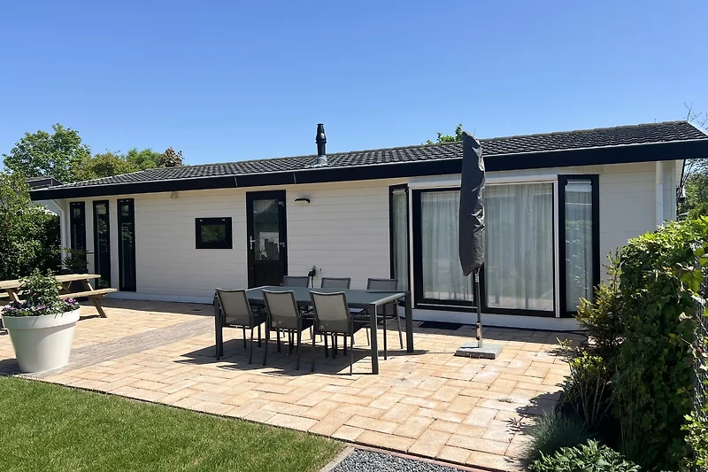 Ferienhaus mit Einfahrt und grünem Gartenbereich.