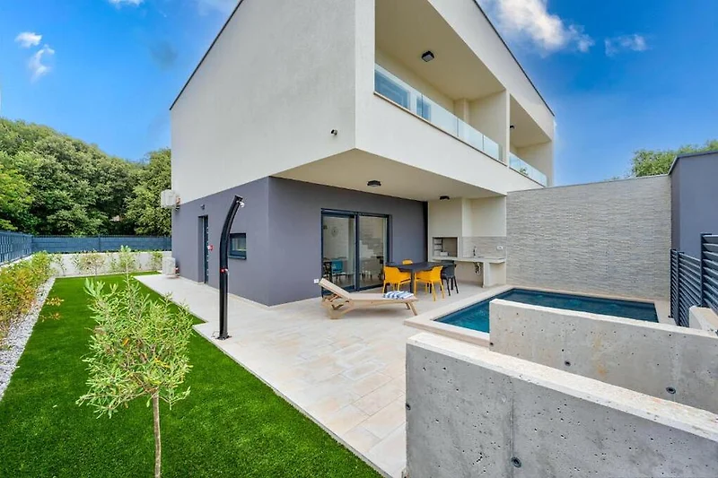 Betonvilla mit schattiger Fassade und viel Tageslicht.