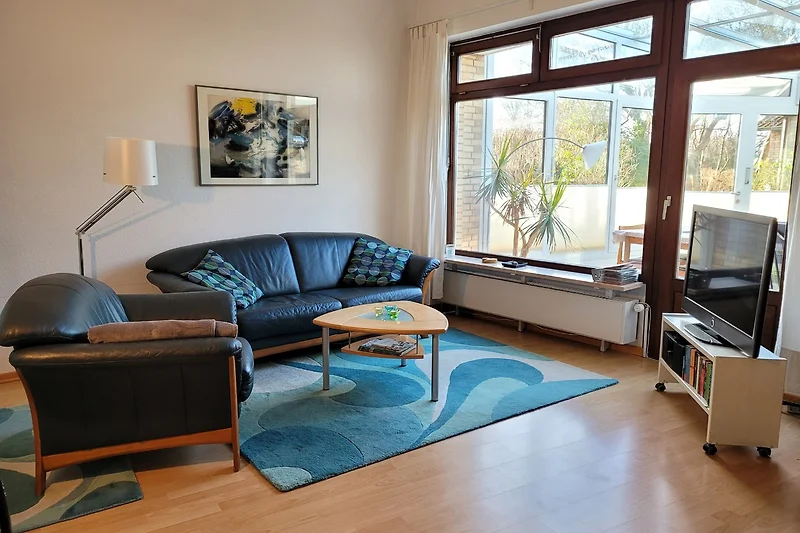Wohnzimmer mit Sofa und Blick in den Wintergarten