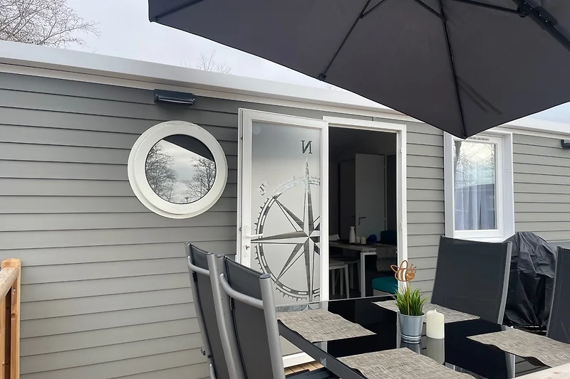Terrasse mit Stühlen und Tisch vor Holzverkleidung