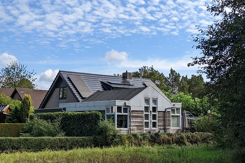 Ländliches Haus unter weitem Himmel und Baum.