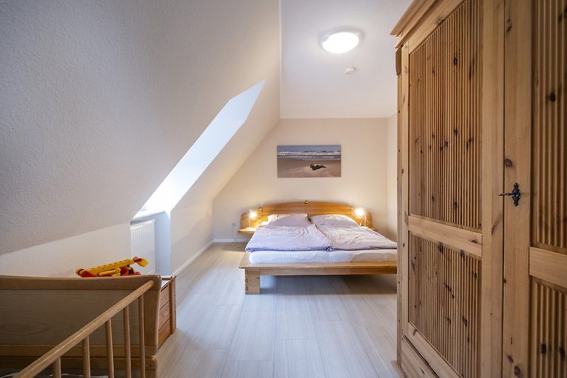 Schlafzimmer mit Holzmöbeln, Bett und Bettwäsche.