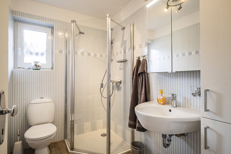 Modernes Badezimmer mit lila Akzenten, Spiegel, Dusche und Toilette.