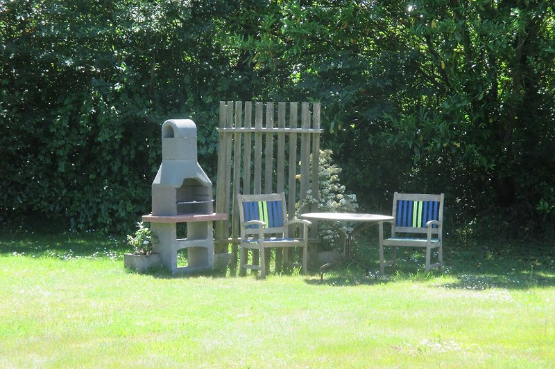 Garten mit Holzmöbeln, Tisch, Stühlen und Barbecue.