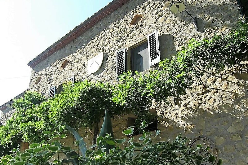 Una casa di campagna con un tetto di tegole, finestre a ghigliottina e un giardino verde.