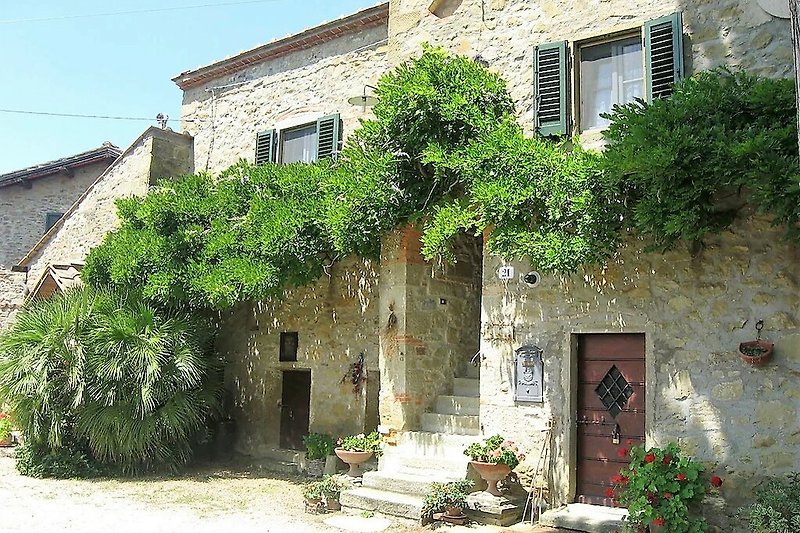Una casa di campagna con un giardino fiorito e un'antica architettura medievale.