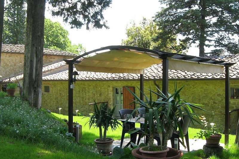 Una casa di campagna con un tetto di tegole, un giardino verde e una vegetazione rigogliosa.