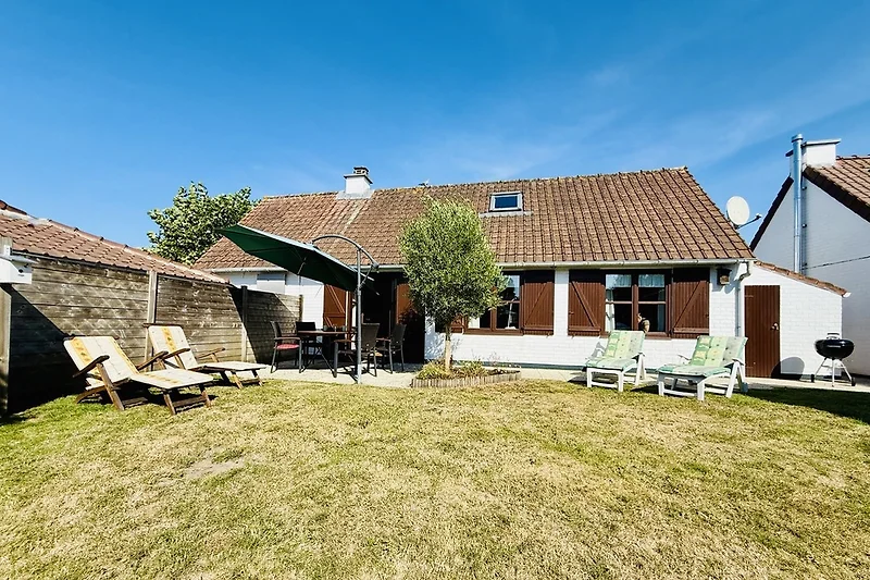 Großer Garten mit Terrasse, Liegestühlen und Blick auf das Landhaus.