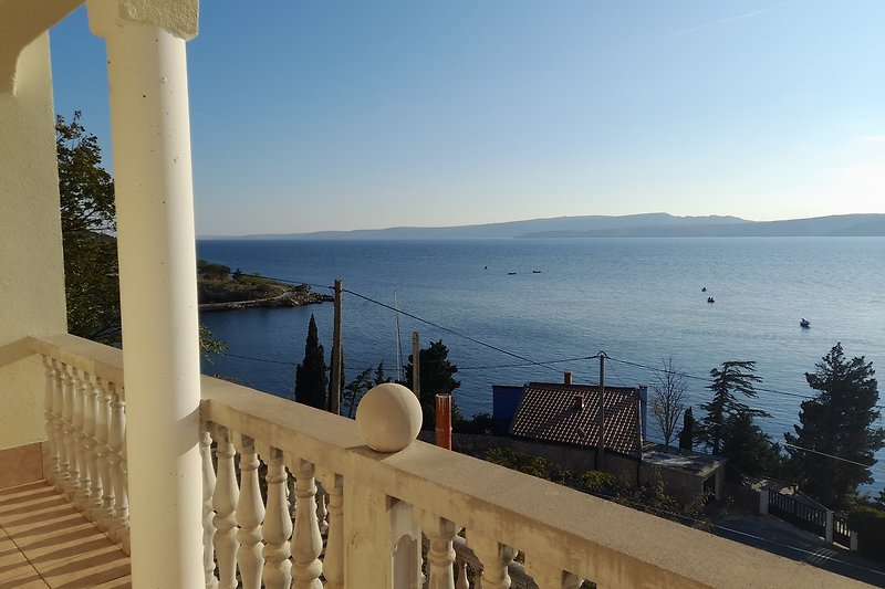 Strandvilla mit Balkon, Meerblick und tropischen Palmen.