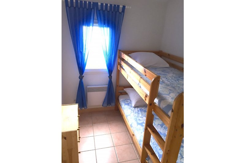 Dječja soba s krevetom na kat, ormarom za odjeću i komodom.