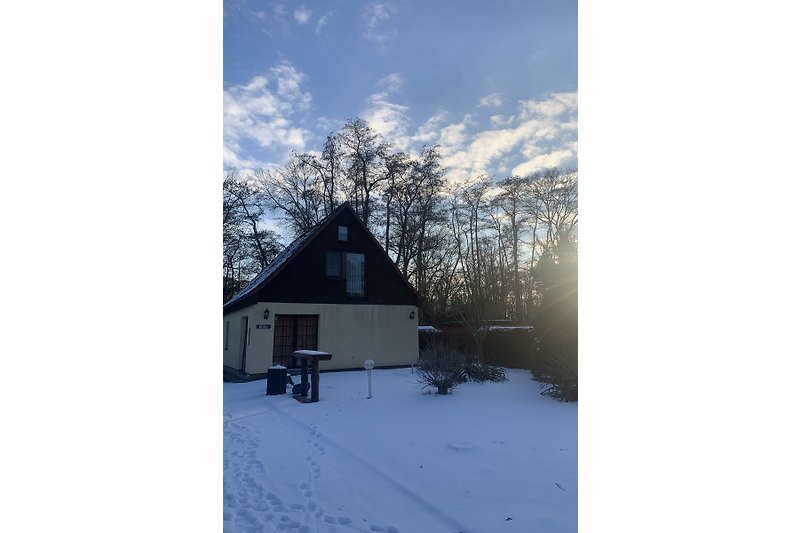 Verschneites Ferienhaus mit Schindeldach und Holzverkleidung.