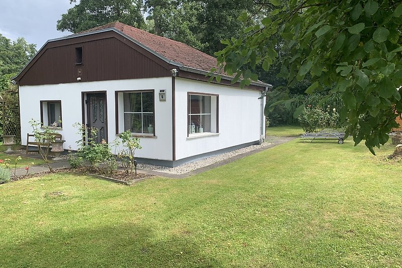 Gemütliches Landhaus mit Garten, Bäumen und blühenden Pflanzen.