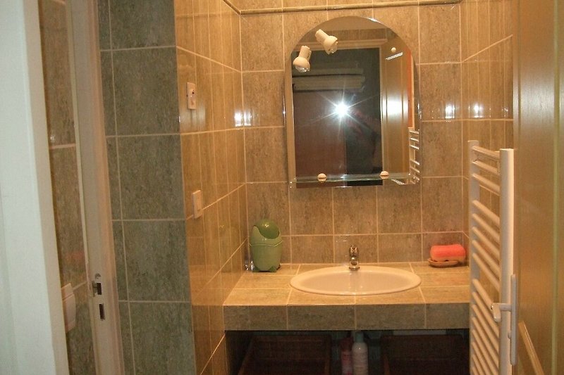 Badezimmer mit Spiegel, Waschbecken und Fliesen.