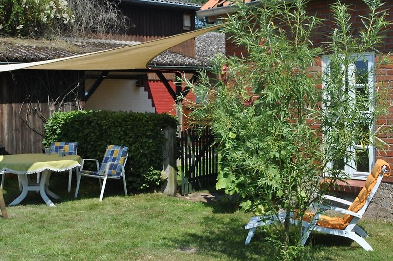 The apartment includes a covered terrace and a seating area in the garden.