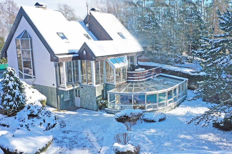 Winterlandschaft mit verschneitem Haus, Fenstern und Dach in einem malerischen Bergdorf.