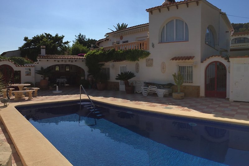 Gemütliches Ferienhaus mit Pool, Palmen und sonniger Terrasse.