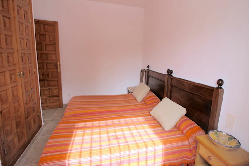 Schlafzimmer mit gemütlichem Bett, Holzmöbeln und Fenster.