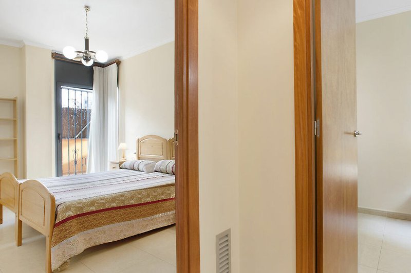 Gemütliches Schlafzimmer mit Holzmöbeln und Lampen. Gemütliches Bett und Fenster.