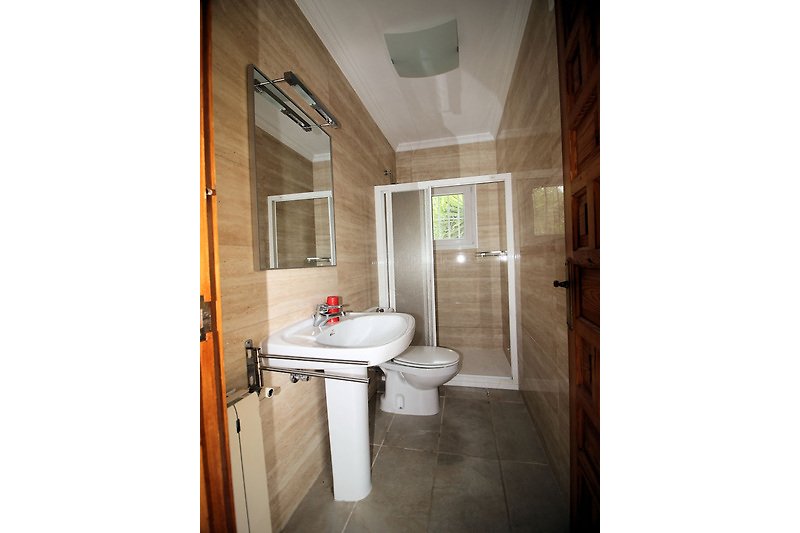 Badezimmer mit lila Akzenten, Spiegel und Toilette.