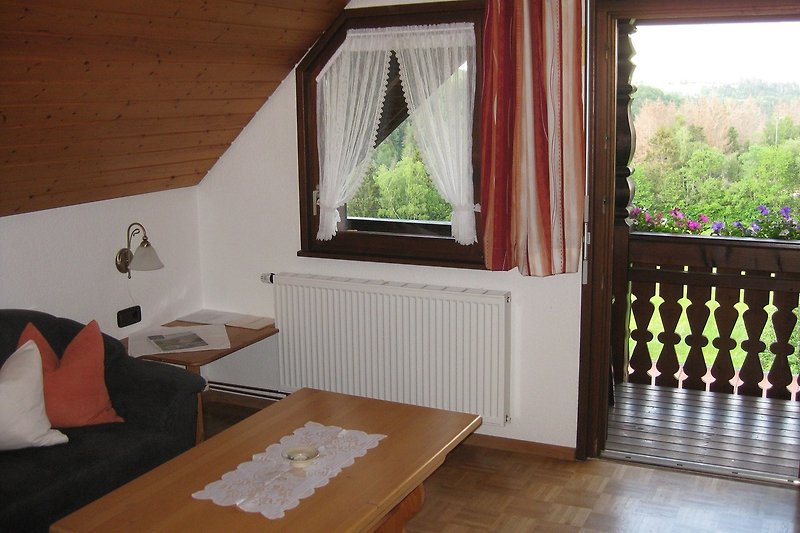 Gemütliches Wohnzimmer mit Holzboden und großen Fenstern.