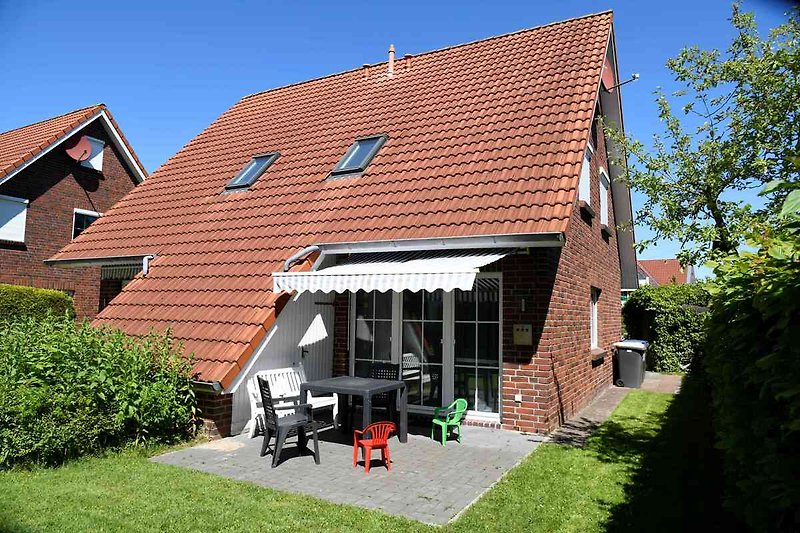 Schönes Landhaus mit Holzfassade, Gartenbank und blühenden Sträuchern.