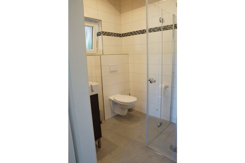 Łazienka z prysznicem na poziomie podłogi, drzwi mogą być składane ze wszystkich stron.