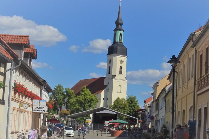 Historische Stadt mit Kirche, Turm, Straße und Bäumen.