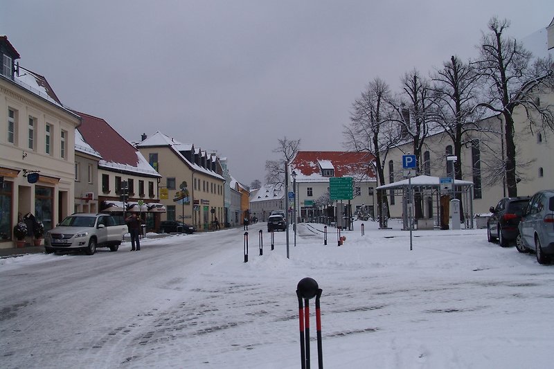 Winterliche Stadtansicht mit Schnee, Gebäude und Straße.