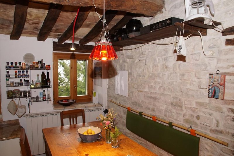 Küchentisch mit freigelegter Natursteinwand, Ingo Maurer lässt grüßen, viele Gewürze, Kaffeemaschine