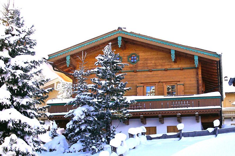Gemütliches Holzhaus mit Winterlandschaft, Schnee und Blick auf die Berge. Perfekt für einen erholsamen Urlaub.
