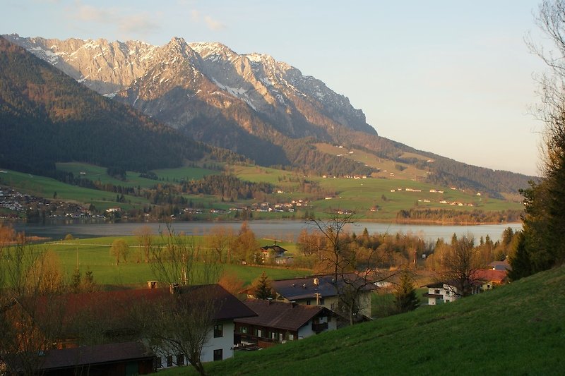 Blick von der Wiese oberhalb des Ferienhauses auf See und Gebirge