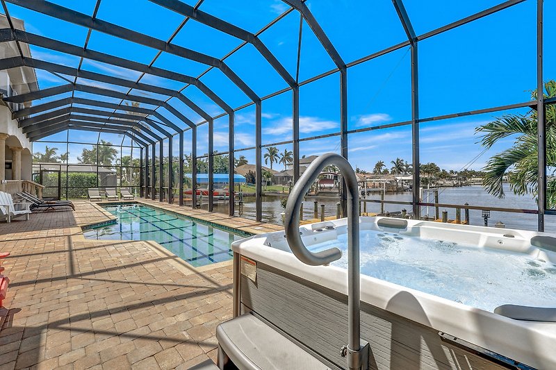 Luxuriöser Pool mit Palmen, azurblauem Wasser und Gebäude.