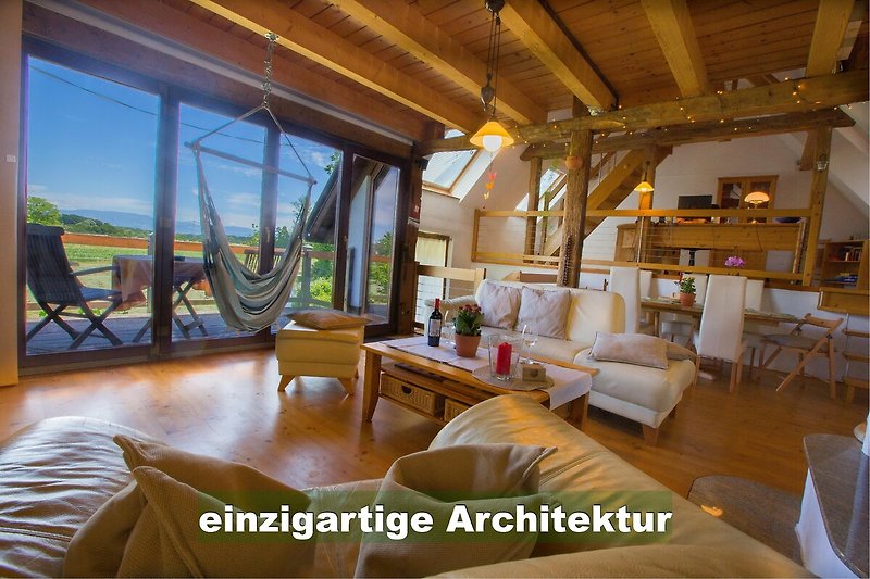 Geräumiges Wohnzimmer mit Holzbalken, gemütlicher Couch und Pflanzen.