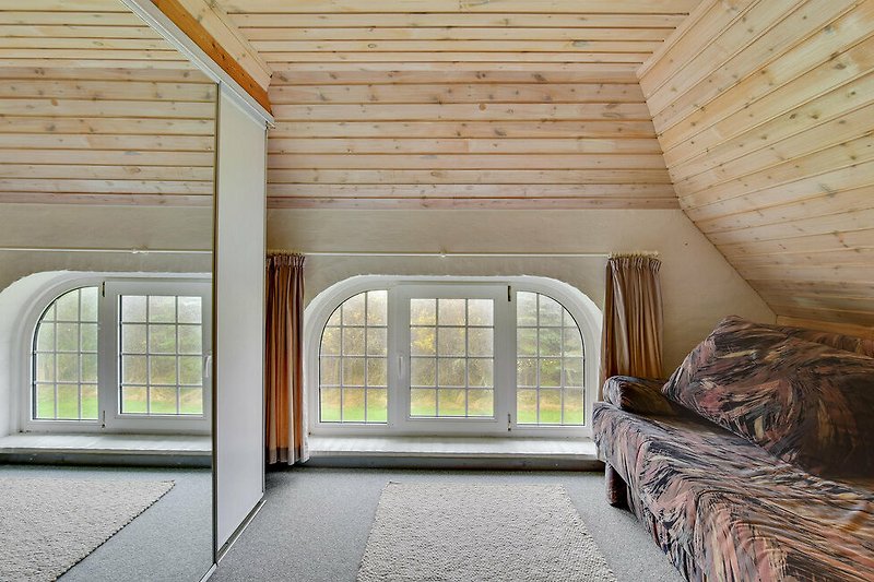 Geräumiges Zimmer mit großen Fenstern und Holzdecke.
