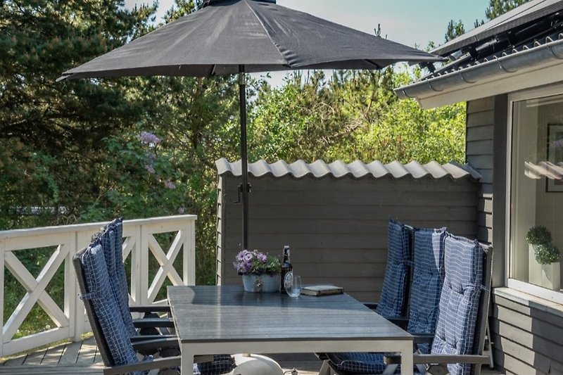 Terrasse mit Möbel und Sonnenschirm.
