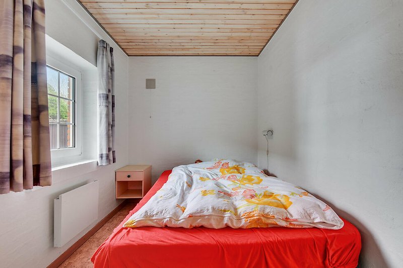 Schlafzimmer mit gemütlichem Bett und Holzdecke.