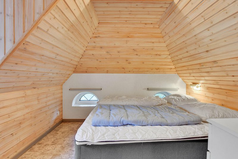Schlafzimmer mit bequemem Bett, Fenster und Holz.