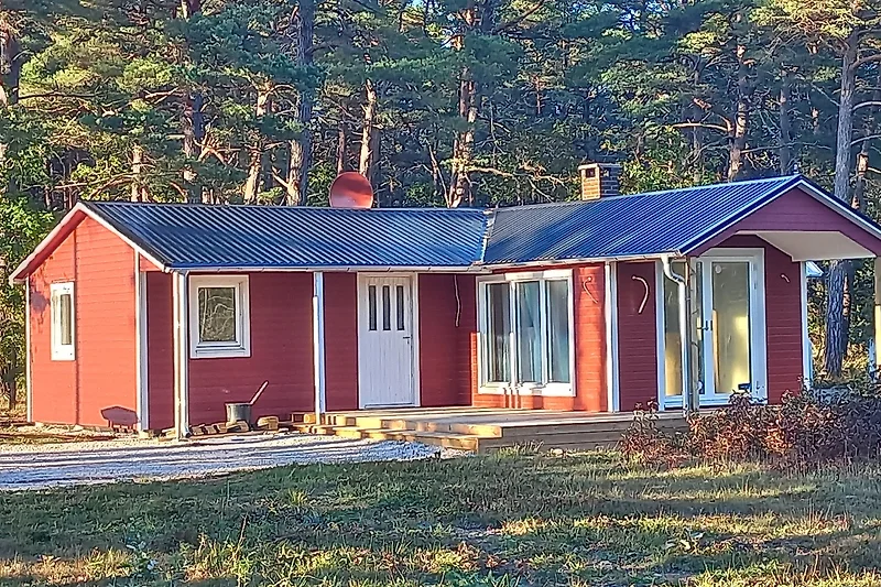 Rustikales Holzhaus mit Veranda und gepflegtem Garten.