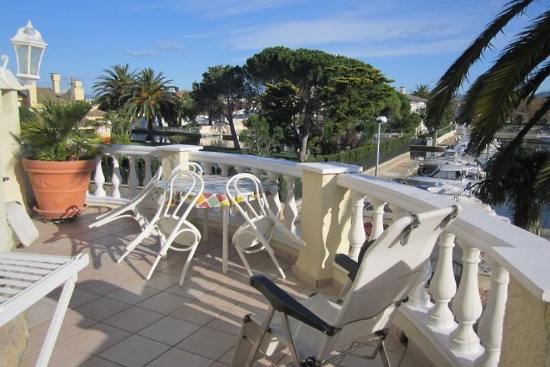 Large round terrace with table set, loungers and sun umbrellas.