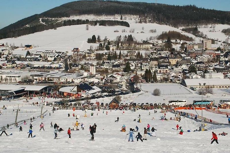 Schneebedeckte Berge, blauer Himmel und Skifahrer auf der Piste. Perfekt für den Winterurlaub!