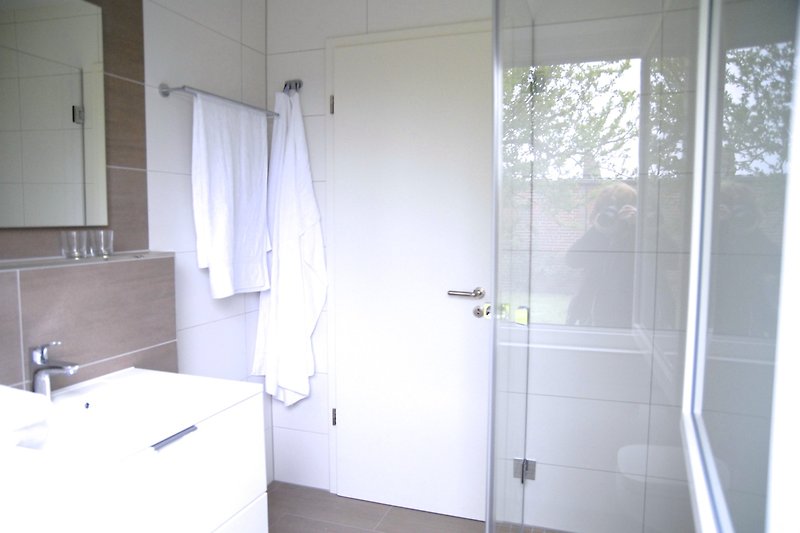 Modernes Badezimmer mit Dusche, Waschbecken und Fenster.