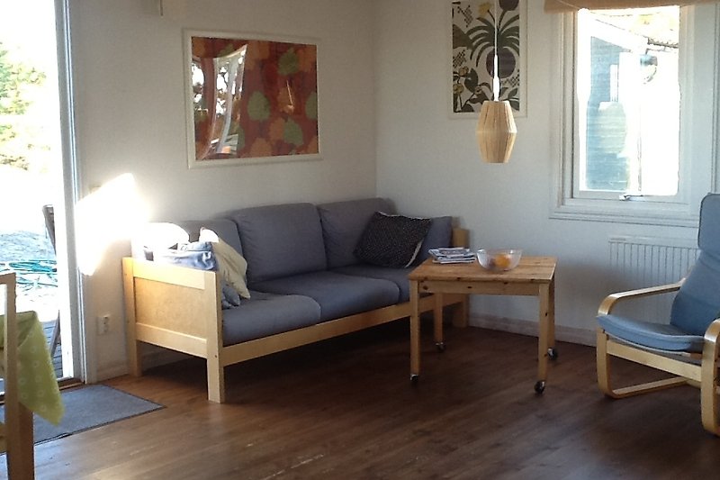 Wohnzimmer mit bequemer Couch, Holztisch und Fenster.