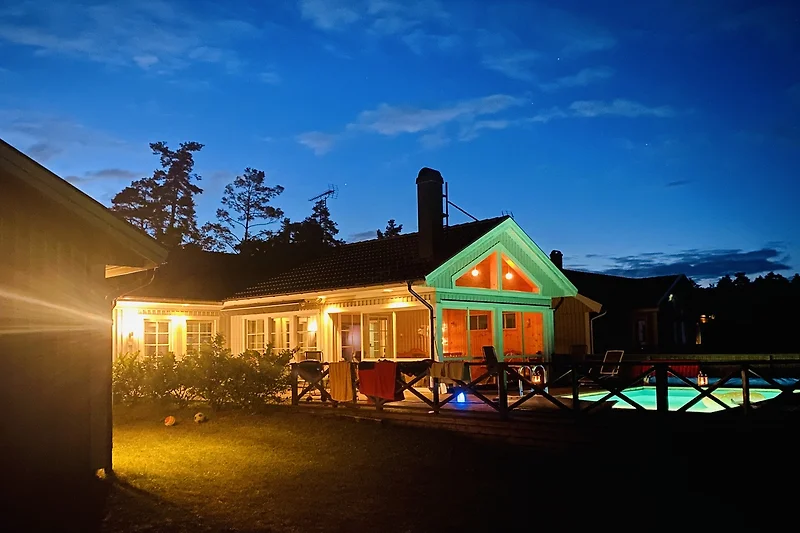 Crepuscolo sopra una casa di campagna con giardino e alberi.
