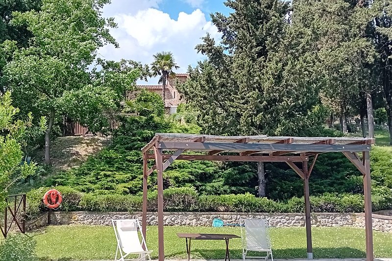 Gemütlicher Garten mit Pergola, Gartenmöbeln und üppiger Landschaft.