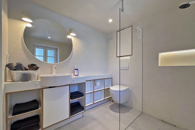 Moderne Badezimmerausstattung mit Spiegel, Waschbecken und Armaturen.