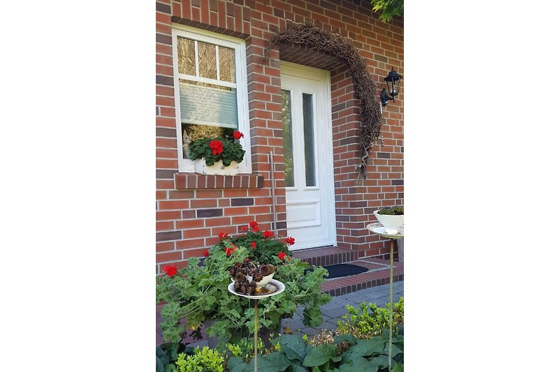 Gemütliches Haus mit blühendem Garten und charmantem Eingangsbereich.