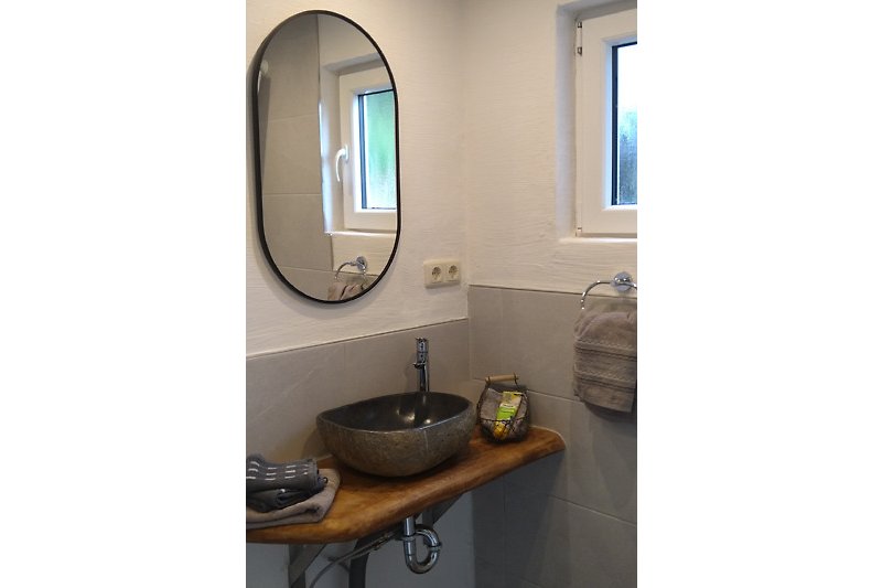 Stilvolles Badezimmer mit elegantem Spiegel und modernem Waschbecken.